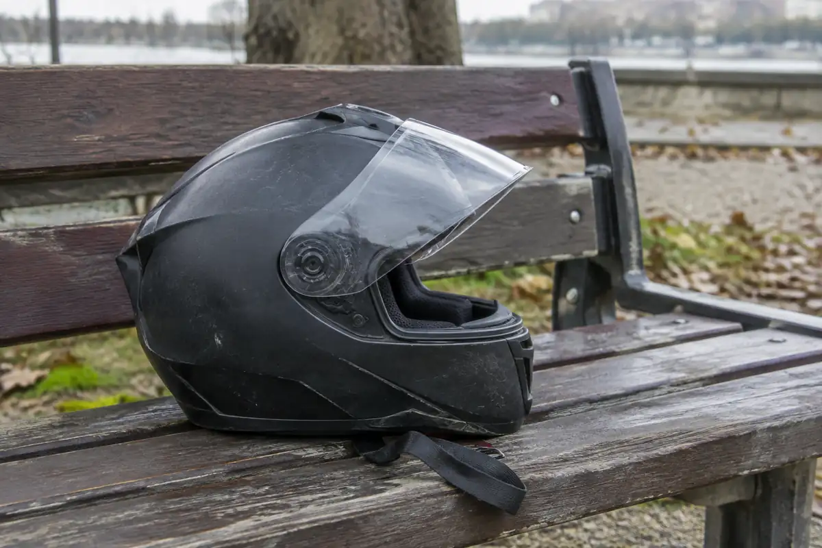 Casque intégral vu de côté, jugulaire détachée, posé sur un banc