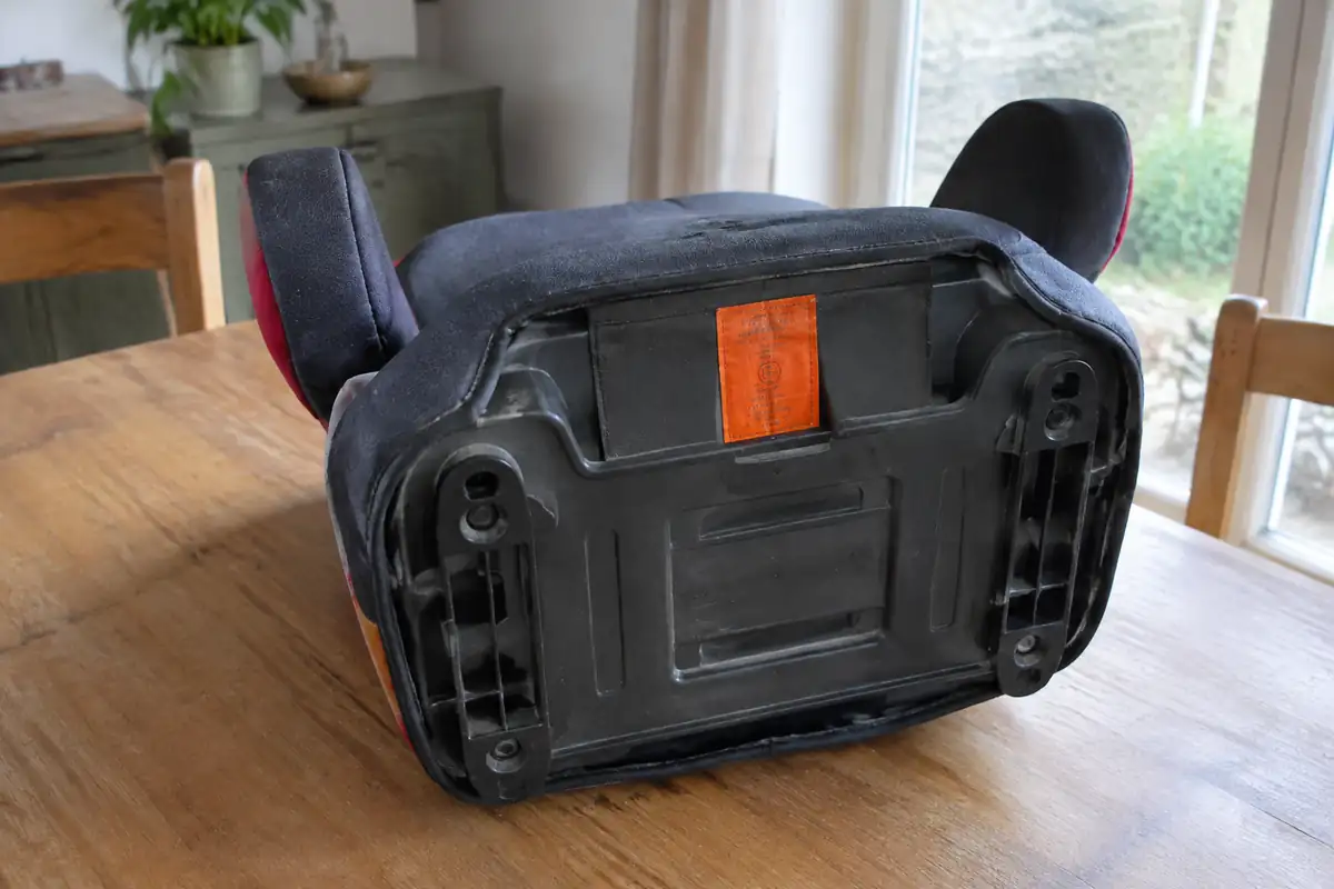 Étiquette d'homologation orange sous l'assise d'un rehausseur