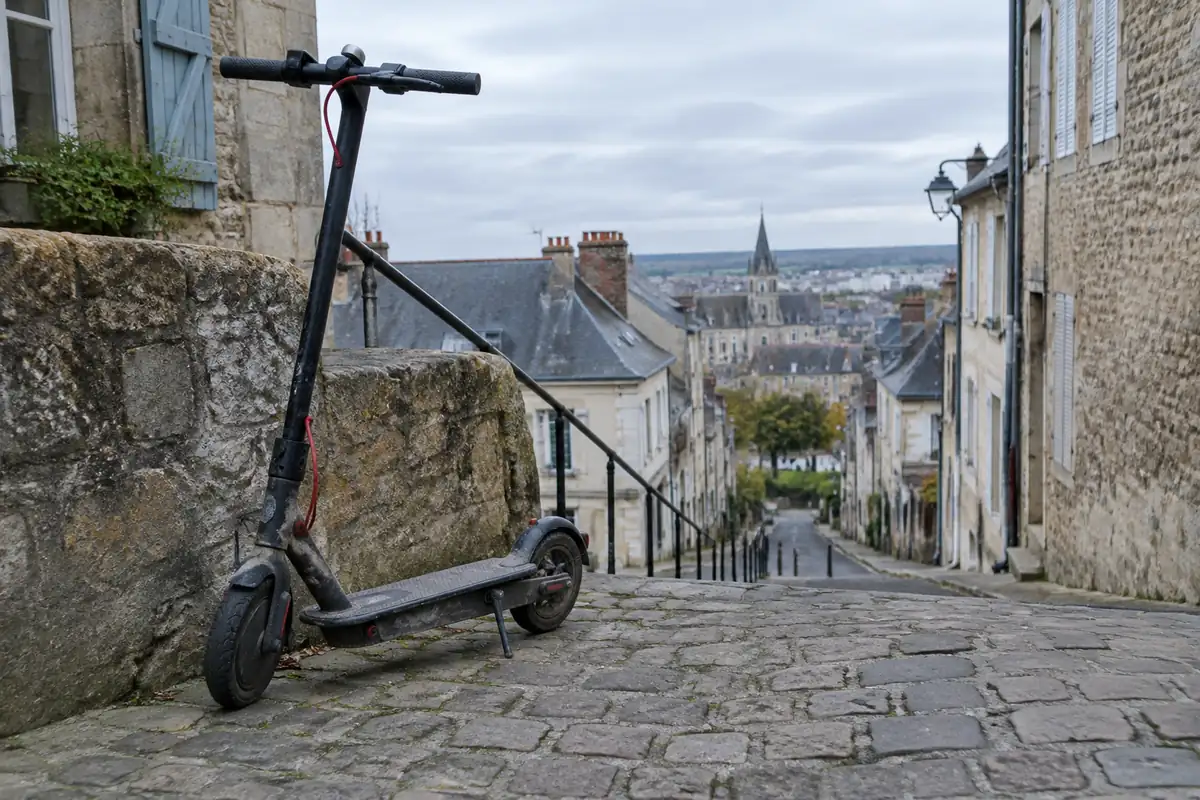 Trottinette électrique garée en haut d'une rue pavée en forte pente